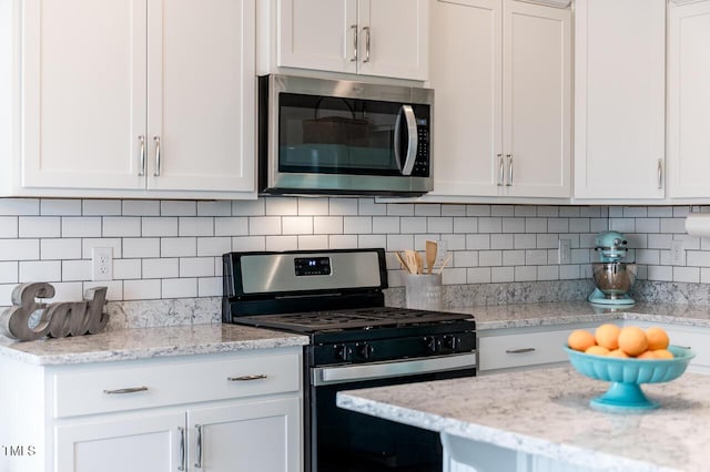 kitchen with stainless steel appliances, light stone countertops, white cabinets, and tasteful backsplash