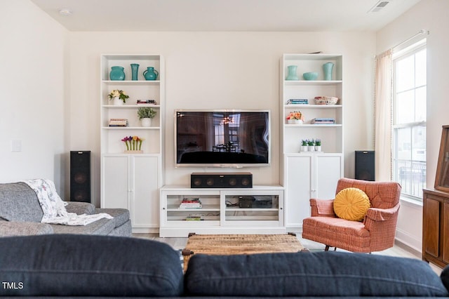 living area with visible vents, built in features, and wood finished floors