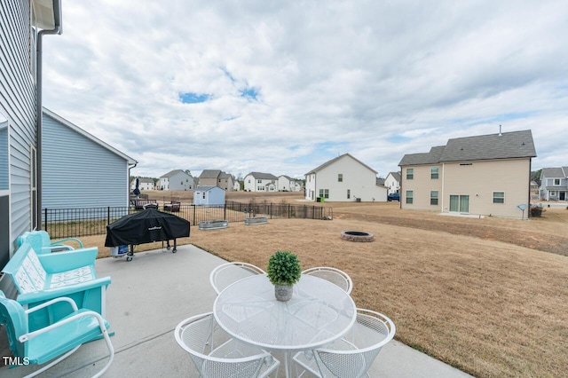 view of patio / terrace with a residential view, a fire pit, fence, and area for grilling