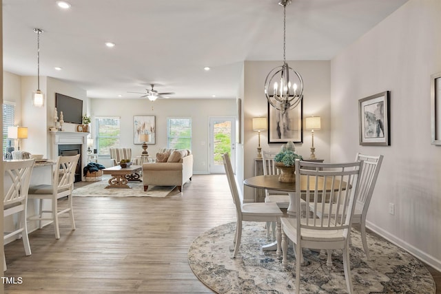 dining space with a fireplace, recessed lighting, a ceiling fan, wood finished floors, and baseboards