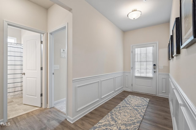 doorway with a wainscoted wall and wood finished floors