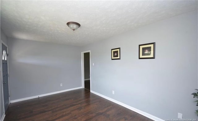 spare room with a textured ceiling, baseboards, and wood finished floors