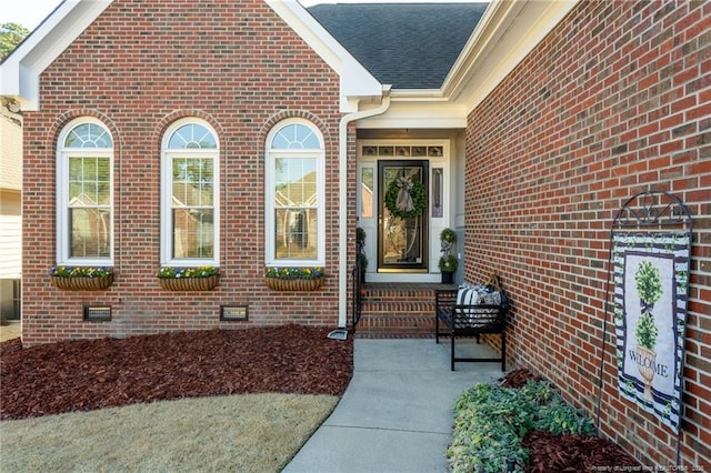 doorway to property with roof with shingles, brick siding, and crawl space