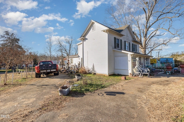 view of side of property featuring driveway and fence