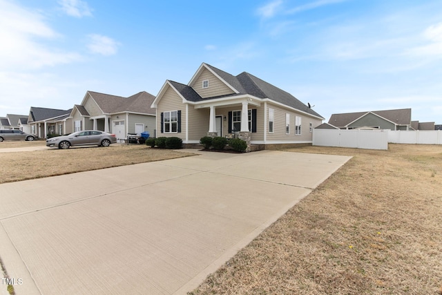 view of front facade with driveway, a porch, a front lawn, and fence