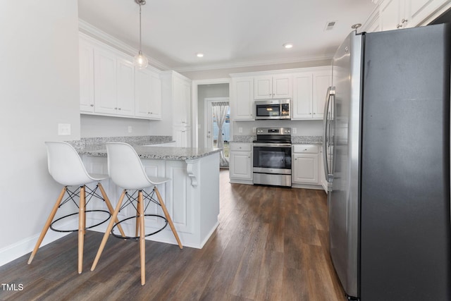 kitchen with a breakfast bar area, a peninsula, white cabinets, appliances with stainless steel finishes, and dark wood-style floors