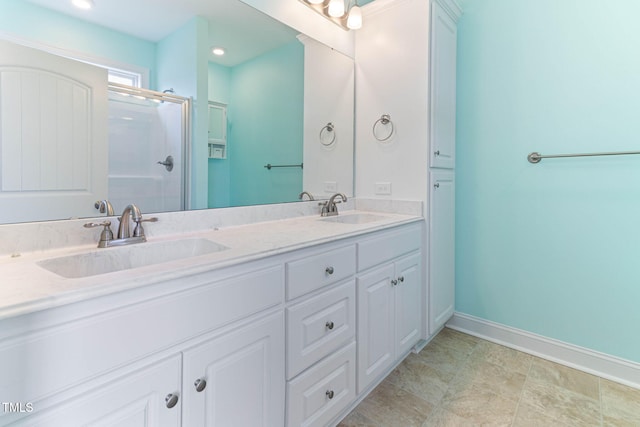 bathroom featuring baseboards, double vanity, a sink, and a shower stall