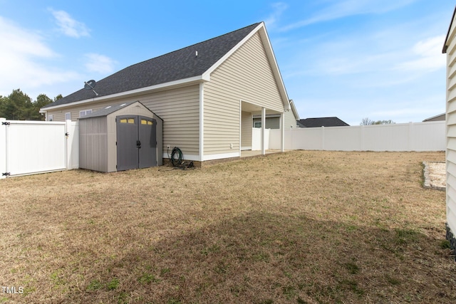 back of house with a lawn, a fenced backyard, an outbuilding, a gate, and a shed