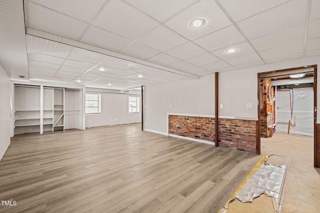 basement with a paneled ceiling, light wood finished floors, and recessed lighting