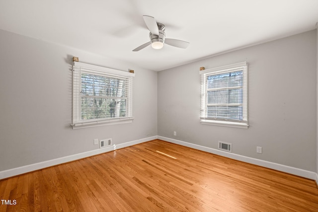 empty room featuring baseboards, visible vents, ceiling fan, and wood finished floors