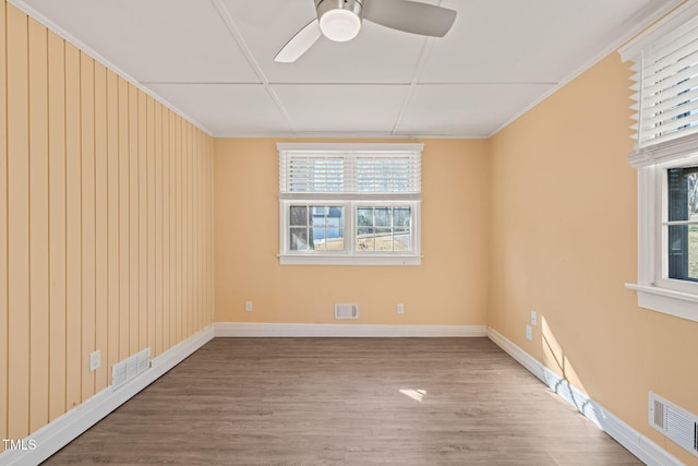 spare room featuring wood finished floors, visible vents, and a healthy amount of sunlight