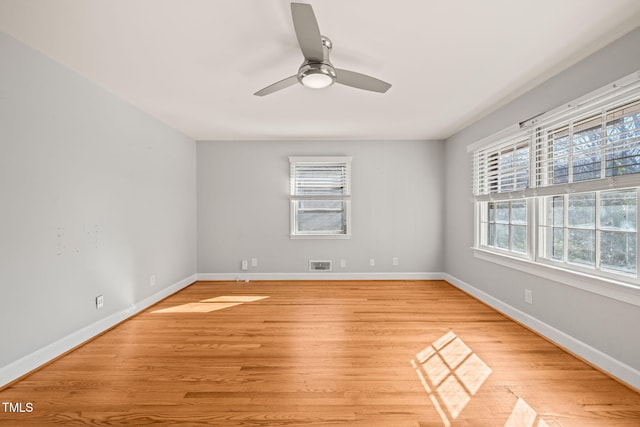 empty room featuring a ceiling fan, light wood-type flooring, visible vents, and baseboards