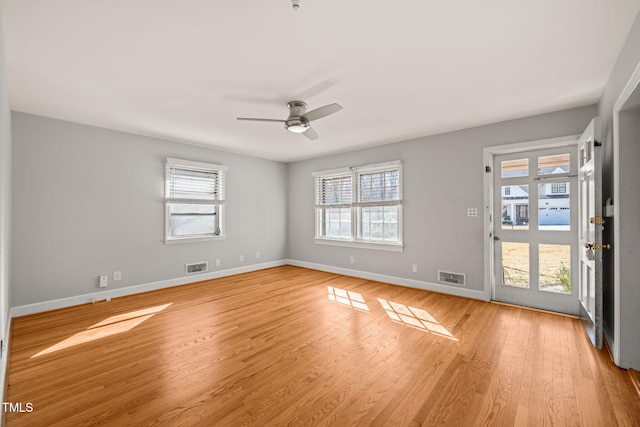 empty room featuring a ceiling fan, light wood-type flooring, visible vents, and baseboards