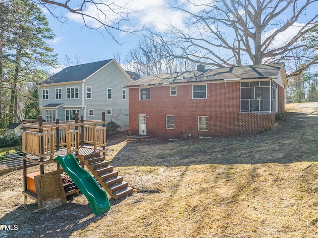 back of house featuring brick siding, a playground, and a chimney