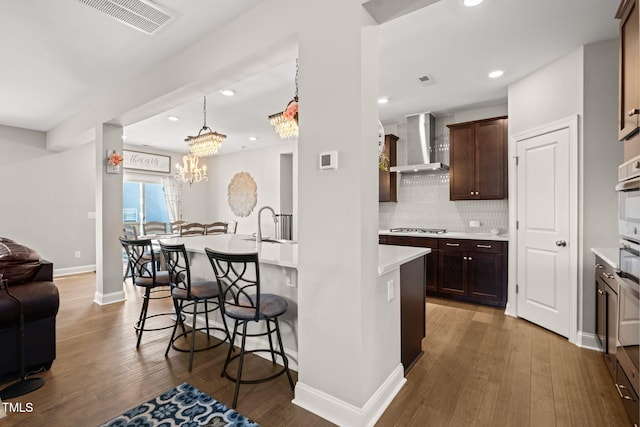 3356 Longleaf Estates Dr, Raleigh, NC 27616 - kitchen with a kitchen bar, open floor plan, stainless steel appliances, dark brown cabinetry, and wall chimney exhaust hood