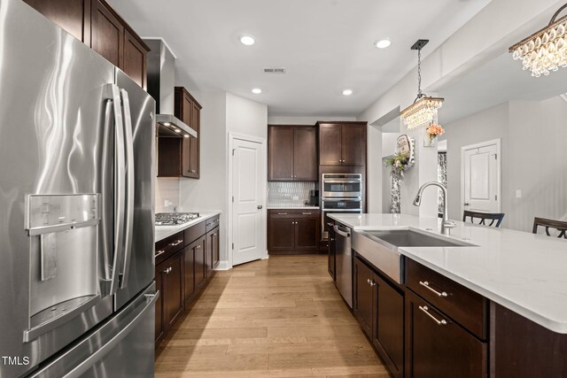 3356 Longleaf Estates Dr, Raleigh, NC 27616 - kitchen with light wood-style flooring, a sink, appliances with stainless steel finishes, wall chimney range hood, and backsplash