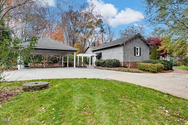 view of side of property featuring driveway, a lawn, and a pergola