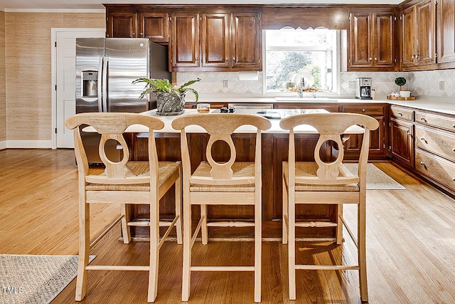 kitchen featuring light countertops, light wood-type flooring, a sink, and crown molding