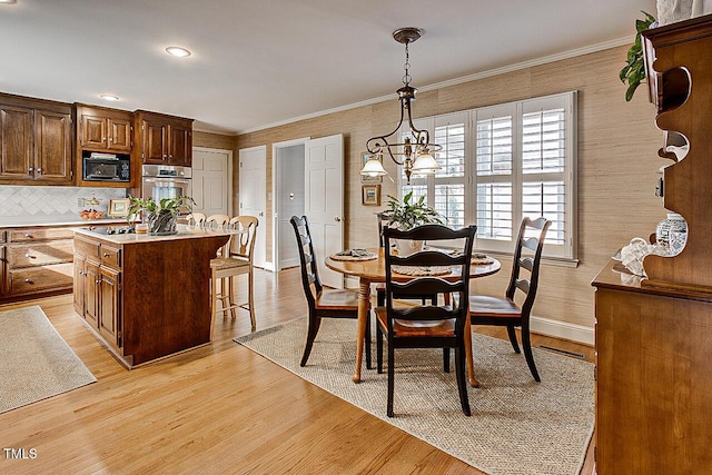 dining area with light wood-style flooring, baseboards, and crown molding