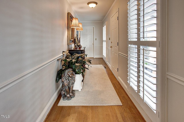 doorway to outside featuring visible vents, crown molding, baseboards, and wood finished floors