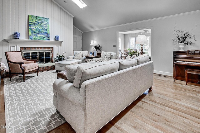 living area with visible vents, ornamental molding, a brick fireplace, vaulted ceiling, and wood finished floors