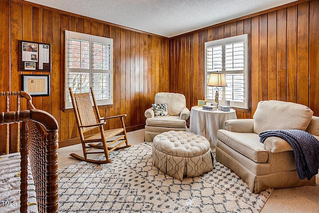 living area with a textured ceiling, wood walls, and carpet flooring