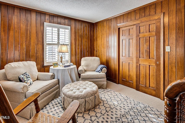 sitting room with carpet floors, wood walls, and a textured ceiling