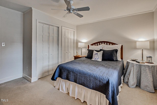 bedroom with baseboards, a ceiling fan, ornamental molding, carpet flooring, and two closets