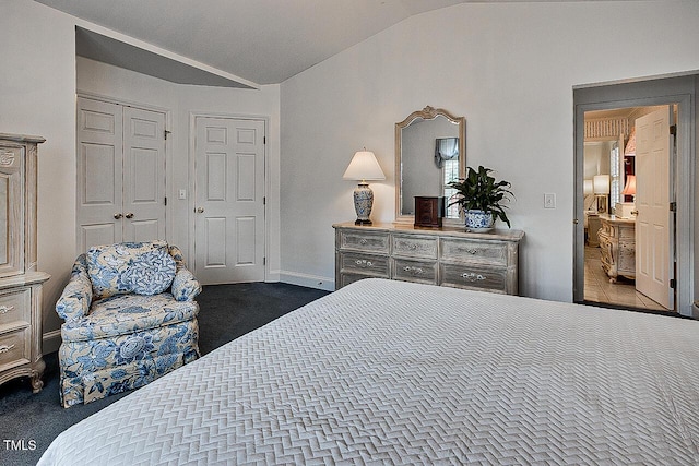 bedroom featuring dark carpet, vaulted ceiling, and baseboards