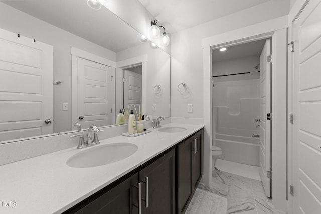 bathroom featuring toilet, marble finish floor, double vanity, and a sink