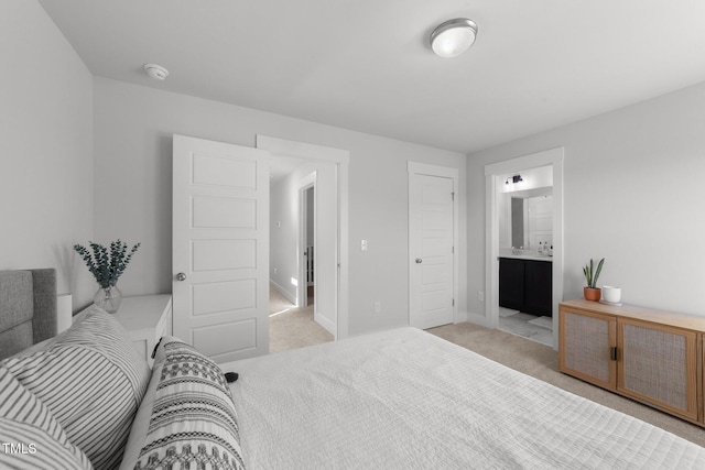 bedroom featuring baseboards, ensuite bathroom, and light colored carpet