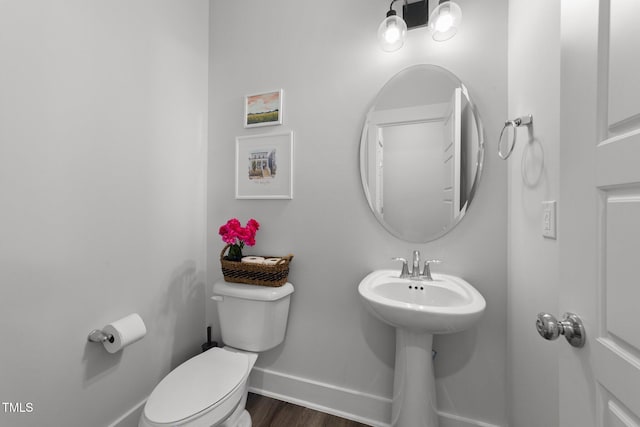 half bath with wood finished floors, toilet, and baseboards