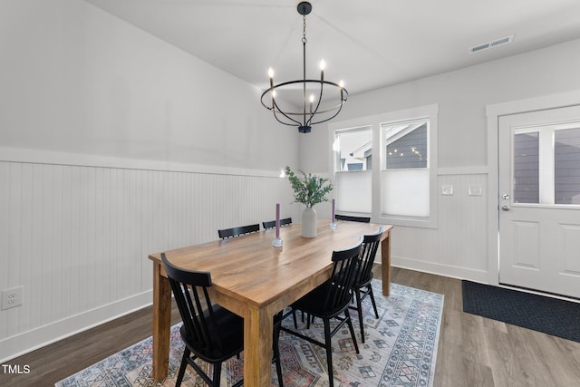 dining area featuring a wainscoted wall, wood finished floors, visible vents, and a notable chandelier