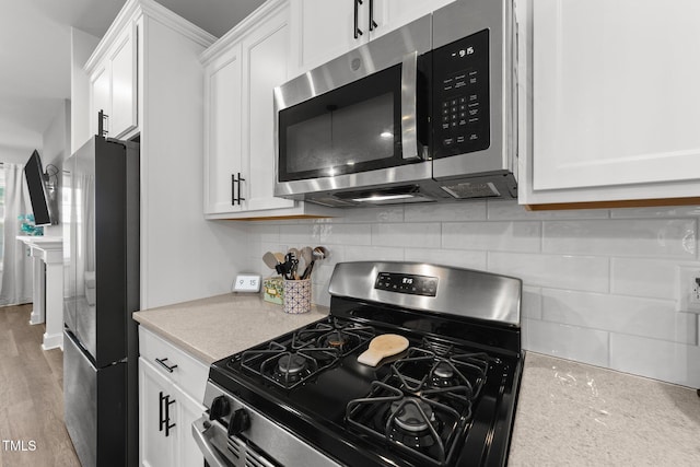 kitchen with stainless steel appliances, white cabinetry, and backsplash