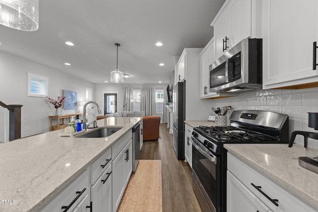 kitchen featuring stainless steel appliances, tasteful backsplash, white cabinetry, a sink, and wood finished floors