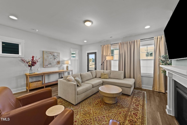 living room featuring dark wood-type flooring, recessed lighting, a fireplace, and baseboards