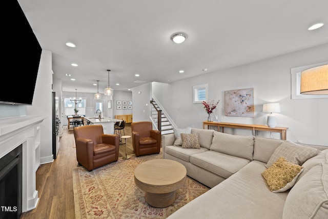 living area with light wood-style flooring, a fireplace, stairway, and recessed lighting