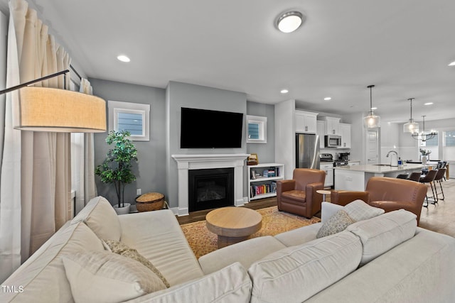 living room featuring a chandelier, a glass covered fireplace, light wood-style flooring, and recessed lighting