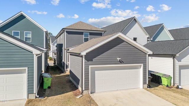 view of front facade with driveway, roof with shingles, and an attached garage