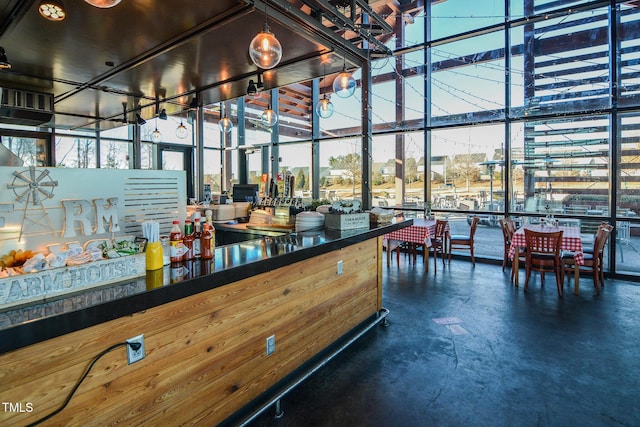 bar featuring concrete flooring, a wood stove, and floor to ceiling windows