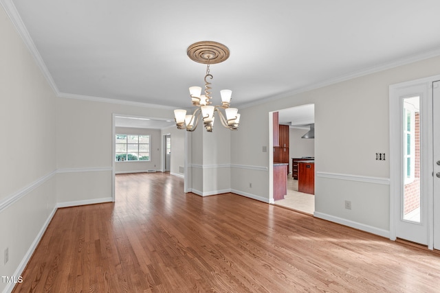 unfurnished dining area featuring baseboards, a notable chandelier, wood finished floors, and crown molding