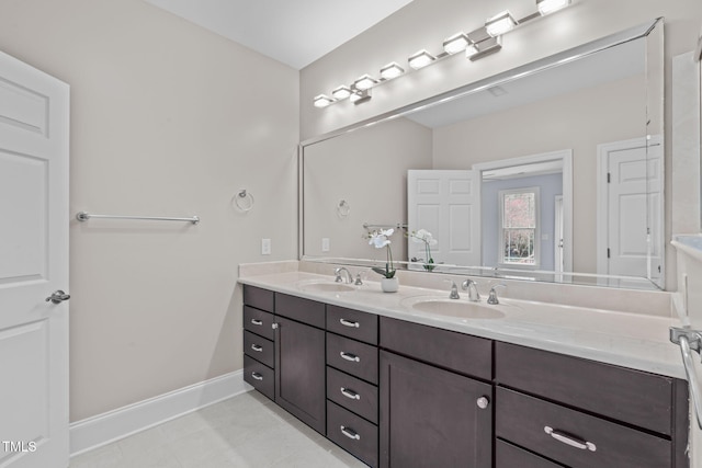 bathroom featuring tile patterned flooring, double vanity, baseboards, and a sink