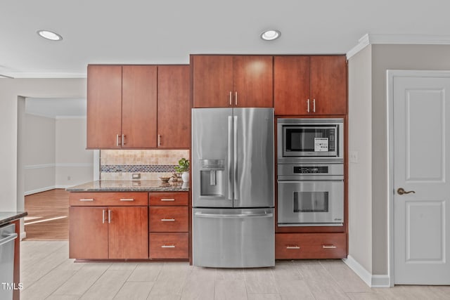 kitchen with ornamental molding, decorative backsplash, brown cabinets, stone countertops, and stainless steel appliances