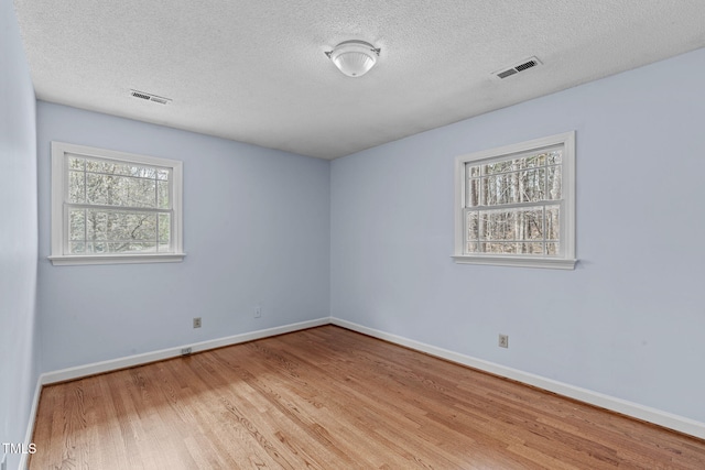 unfurnished room featuring visible vents, baseboards, and wood finished floors