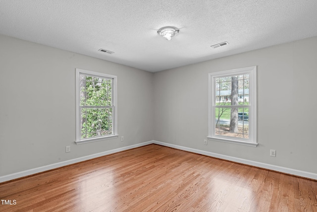 unfurnished room with visible vents, baseboards, and wood finished floors