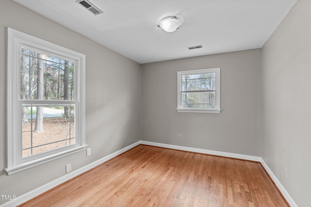 unfurnished room featuring wood finished floors, baseboards, and visible vents