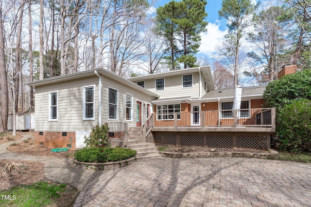 view of front of property featuring a wooden deck, brick siding, and crawl space