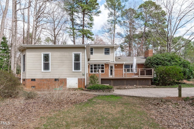 view of front of house featuring a wooden deck, a chimney, driveway, and crawl space