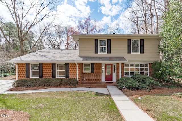 traditional-style home featuring brick siding, roof with shingles, and a front yard