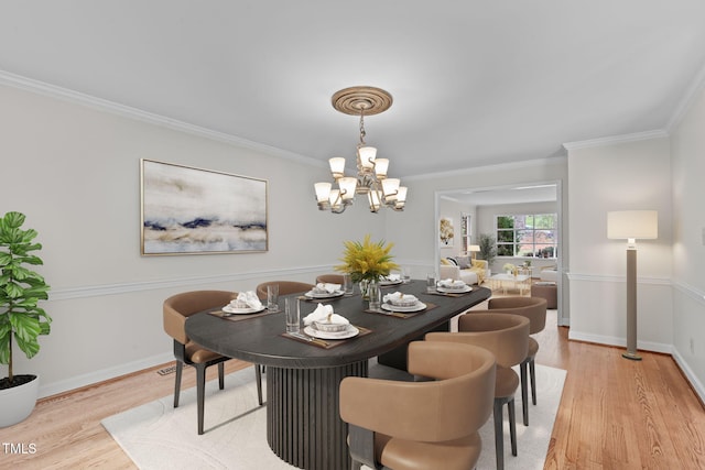 dining room with light wood-style flooring, a notable chandelier, baseboards, and ornamental molding